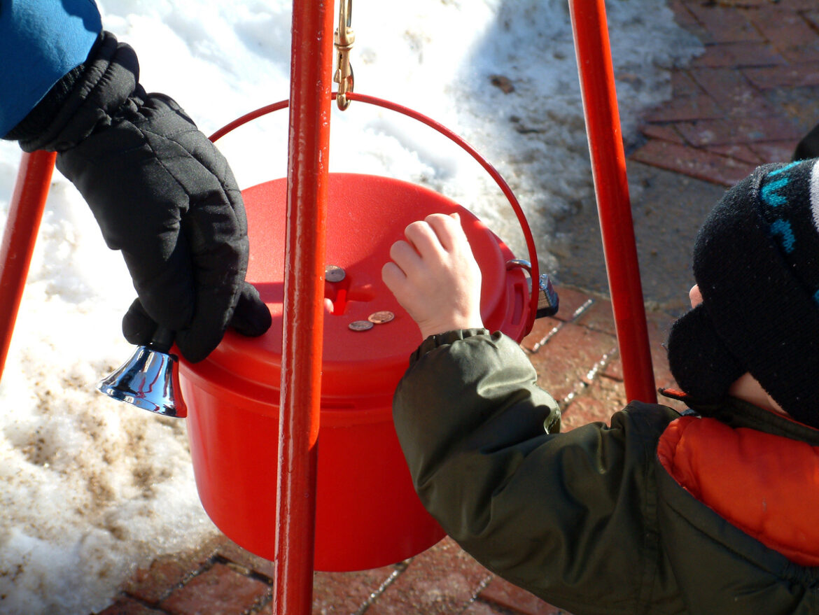Above view of hands dropping money in a red bucket