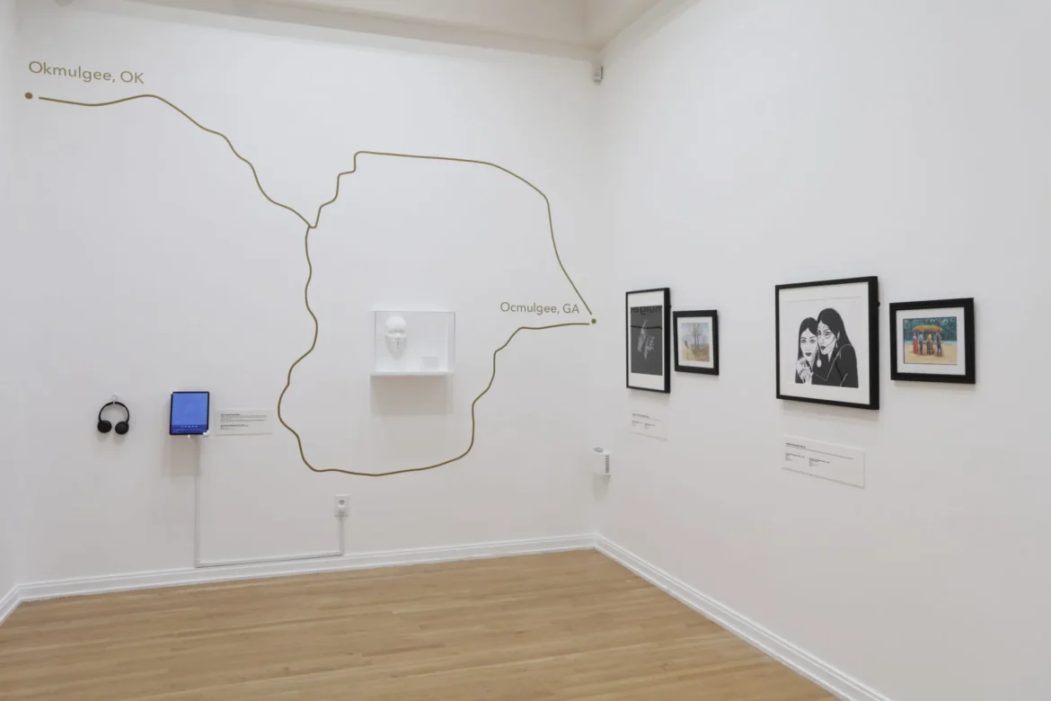 Gallery wall featuring a map connecting Okmulgee, Oklahoma, and Ocmulgee, Georgia, alongside framed artworks and Harjo’s audio station.