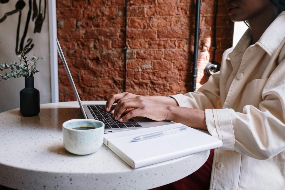 A woman is working at her laptop in a coffee shop.