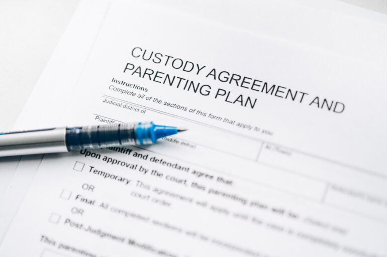 A printed custody agreement and parenting plan with a pen