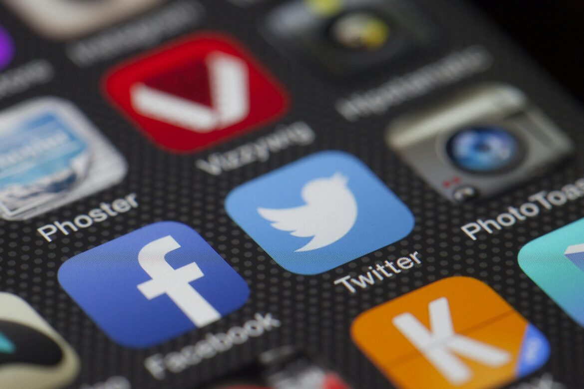 A close up image of a phone screen showing applications like Facebook and Twitter
