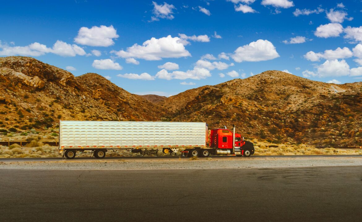 A semi-truck driving on a highway in front of desert mountains
