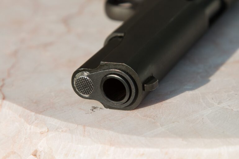 A close up image of a barrel of a pistol sitting on a table