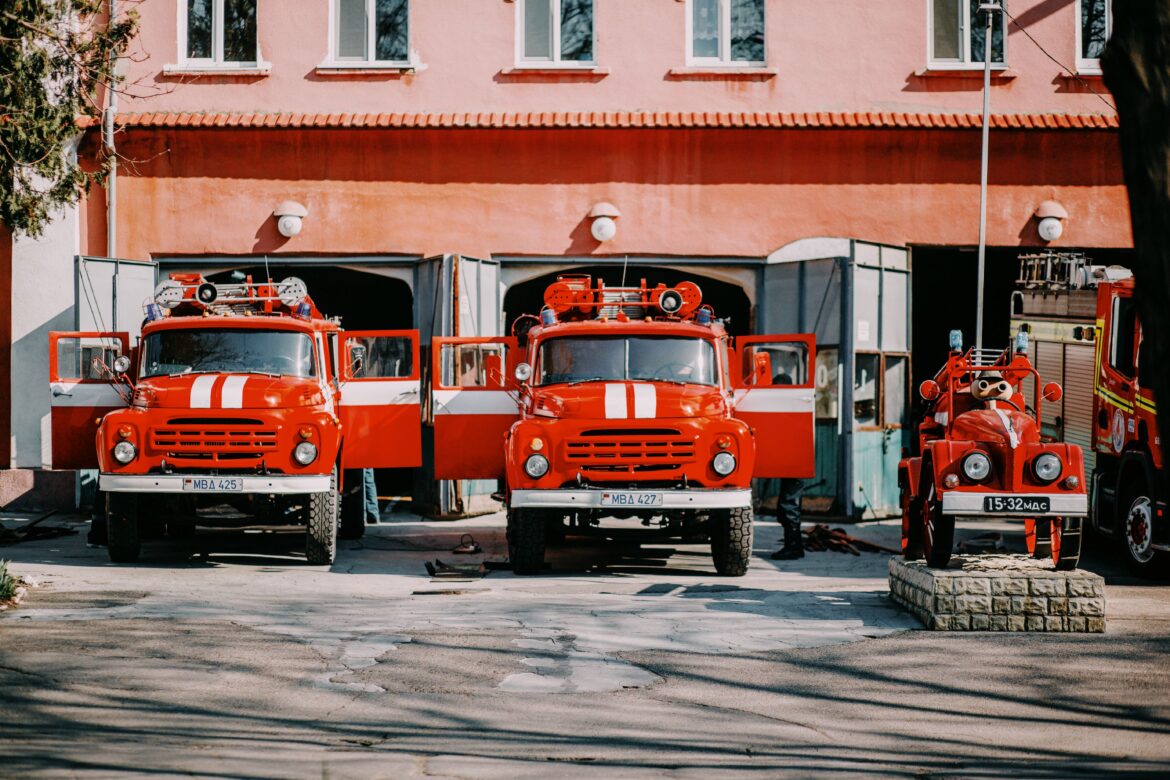 Two old fire trucks parked in front of a fire department