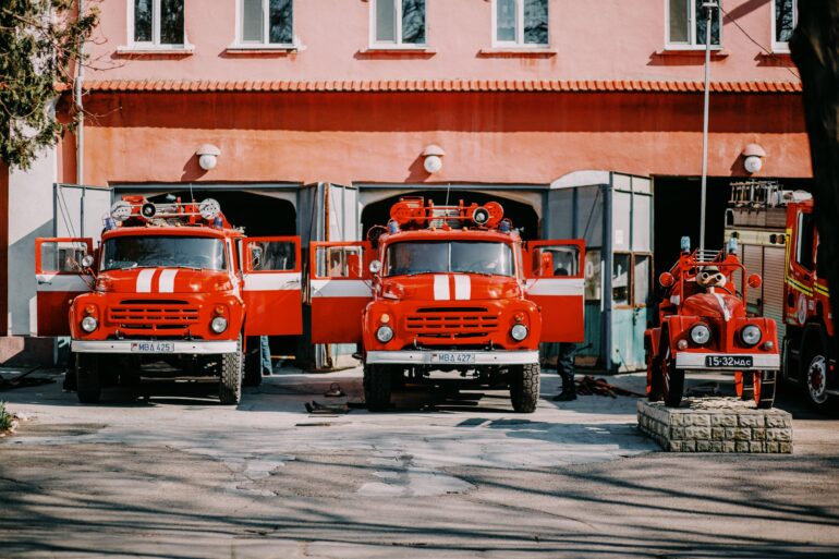 Two old fire trucks parked in front of a fire department